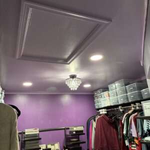 A stylish purple closet featuring organized clothing, storage bins, and a decorative chandelier.