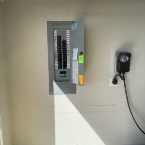 Electrical panel with labeled circuit breakers and a wall-mounted EV charger on a light-colored wall.