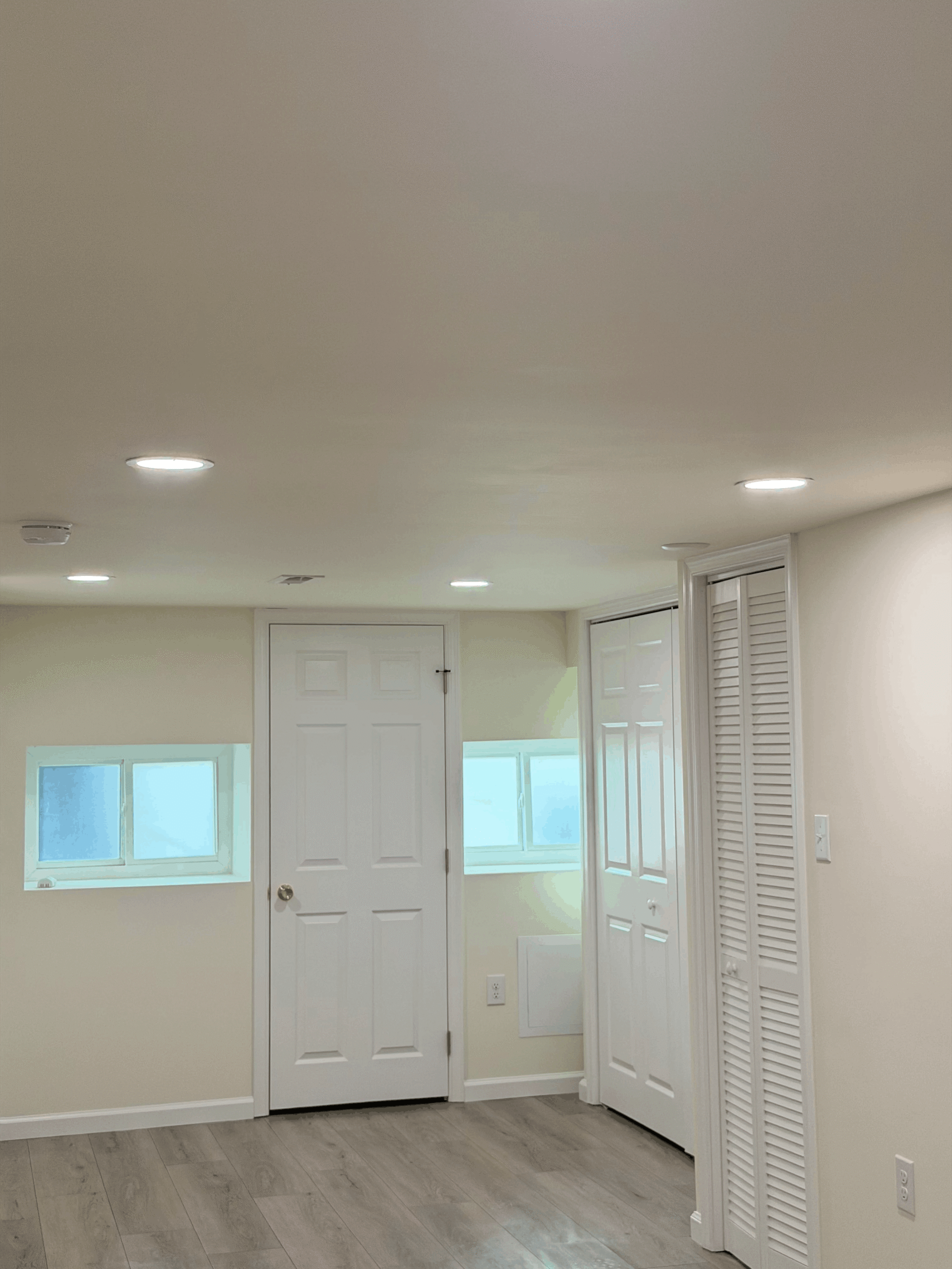 Bright, modern basement room featuring white walls, recessed lighting,